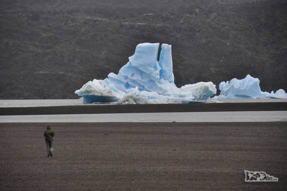 A Ana atravessa praia do lago Grey rumo a um iceberg, no parque Nacional Torres del Paine, no sul do Chile